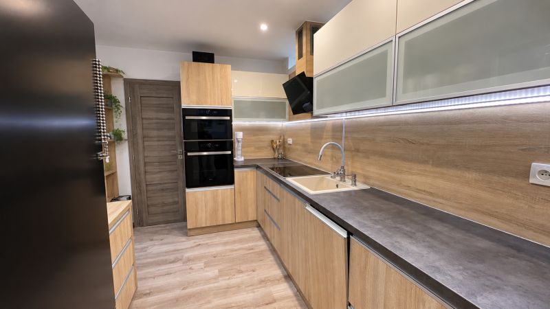 A kitchen in a 3-room apartment with a wooden decor floor and built-in appliances.