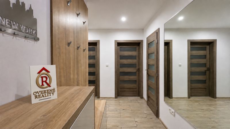 A hallway with wood-patterned flooring, a mirror, and doors in a 3-room apartment.