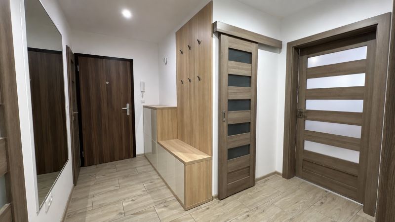 A hallway in a 3-room apartment with a wooden decor floor and furniture.