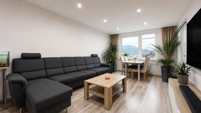 Living room in a 3-room apartment with a sofa, dining table, and wooden decor flooring.