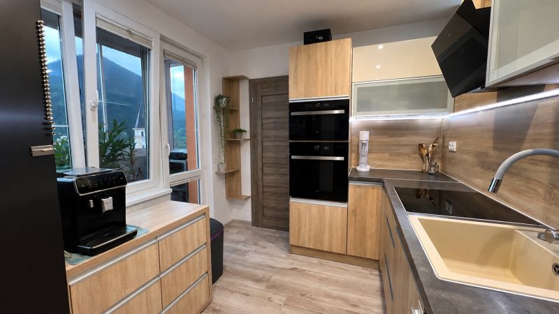 A kitchen in a 3-room apartment with a wooden decor floor and modern equipment.