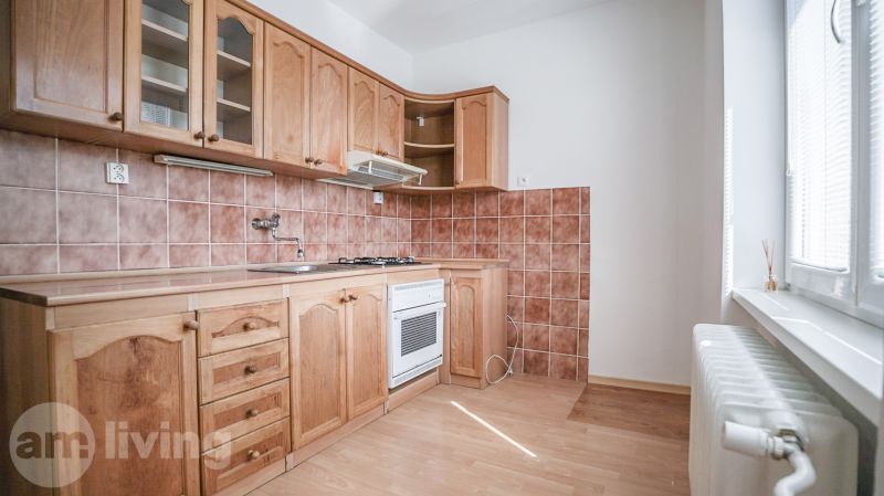 A kitchen in a 2-room apartment with wooden decor and brown tiles.