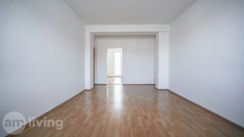A spacious room in a 2-room apartment with a wooden decor floor.