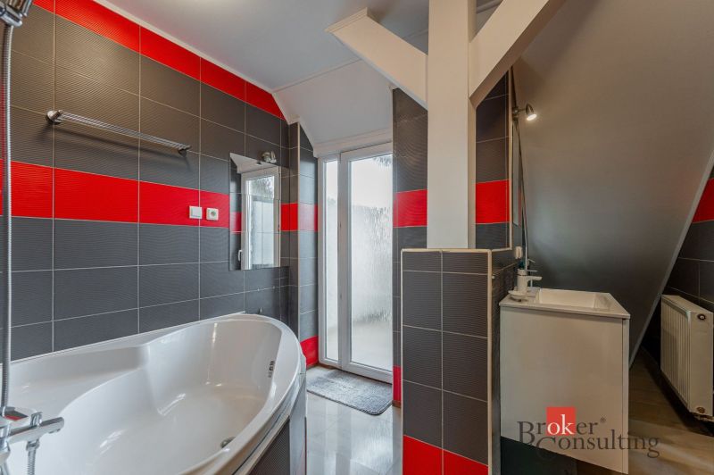 A bathroom with a bathtub and a sink in a 3-room apartment, featuring striking black and red tiles.