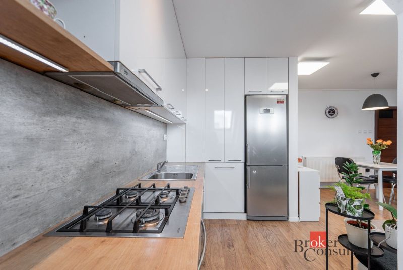 A kitchen in a 3-room apartment with a stainless steel refrigerator and a cooktop, flooring with a wood decor.
