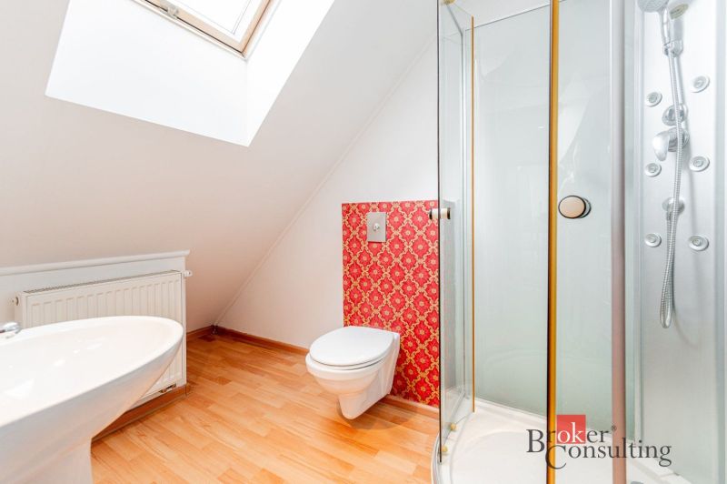 A bathroom in a 3-room apartment with tiles, a shower corner, and a floor with a wooden decor.