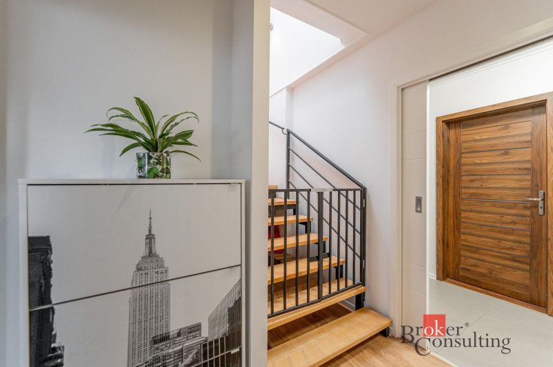 A hallway in a 3-room apartment with a decorative cabinet and a staircase with a wooden decor.