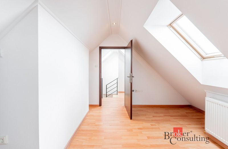 An attic room of a 3-room apartment with a wooden decor floor and a skylight.