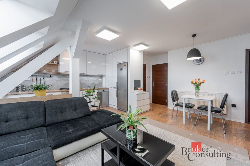 Living room with wood-patterned flooring and a kitchenette in a three-room apartment.