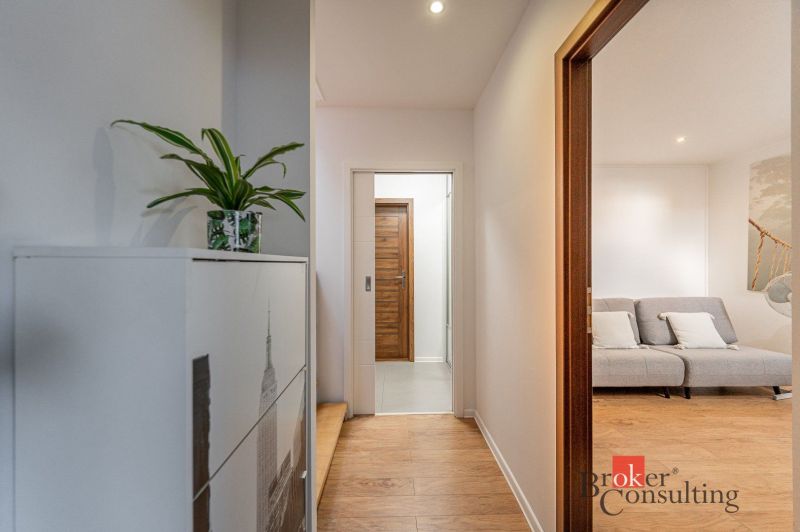 A hallway with an entrance to the living room and a wooden decor floor in a 3-room apartment.