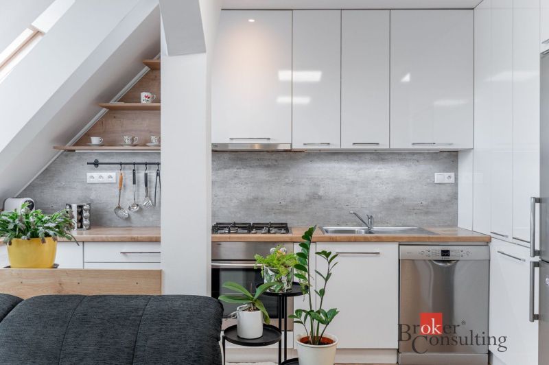 A kitchen corner in a 3-room apartment with plants and cabinets with a glossy finish.