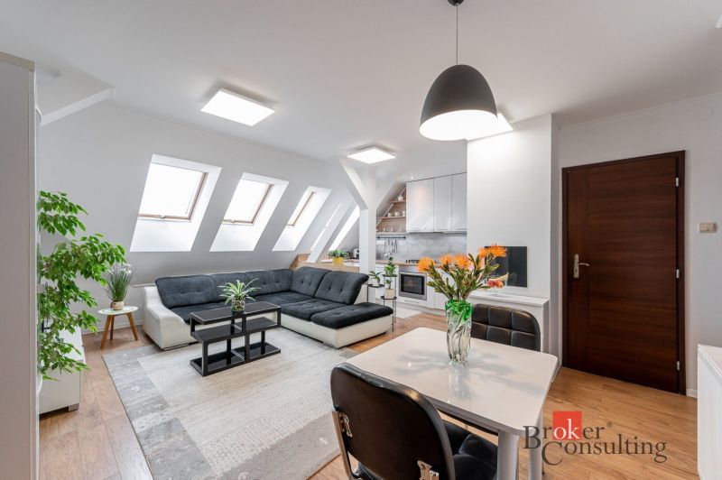 Living area of a 3-room apartment with a sofa, table, and wooden decor flooring.