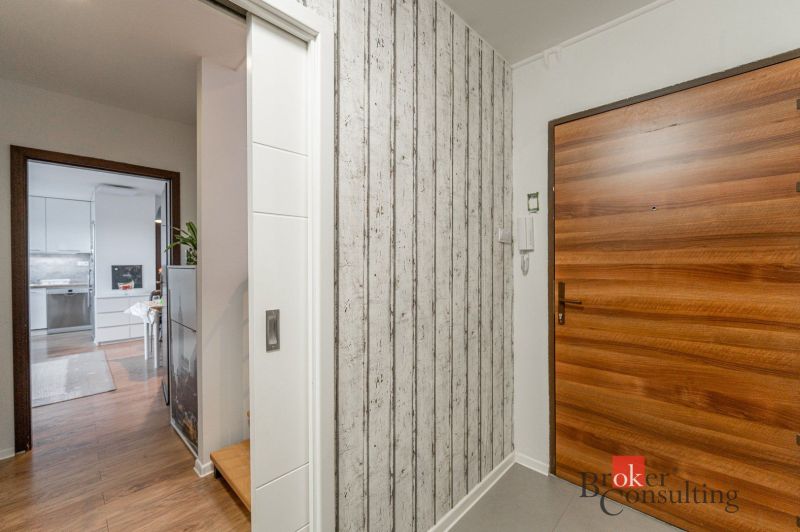 A hallway of a 3-room apartment with wooden doors and a floor with a wooden decor.