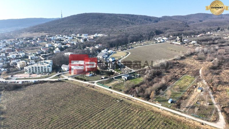 Aerial view of vineyards and houses in the Záhrad area in Bratislava III, surrounded by hills.