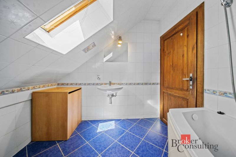 A bathroom with a sloped ceiling, blue floor, wooden door, and cabinet.
