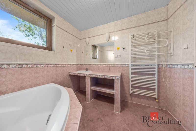 Bathroom with a bathtub, sink, and radiator, tiled with a window.