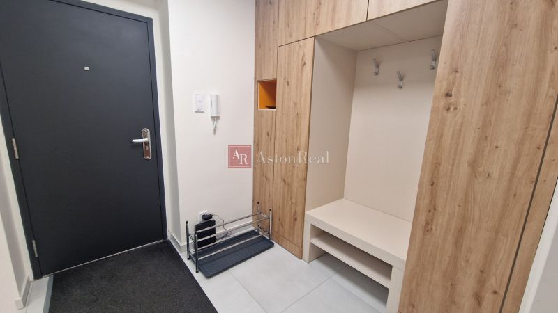 Entrance hallway in a 3-room apartment with a storage system and dark doors.