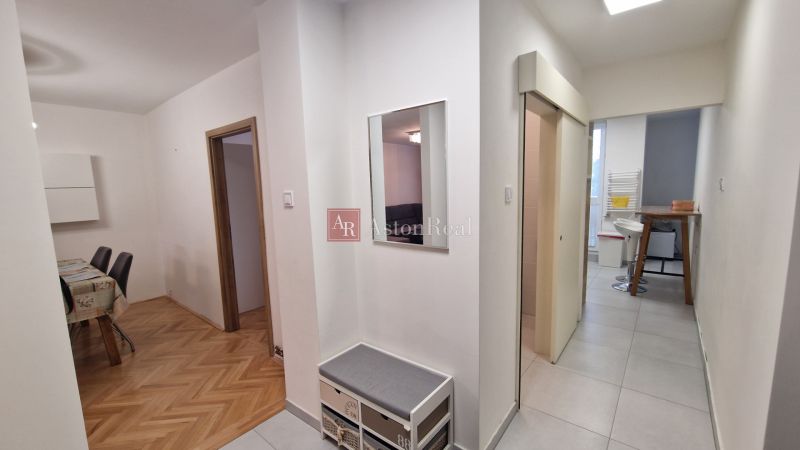 A hallway in a 3-room apartment with a wooden decor floor and a table in the background.