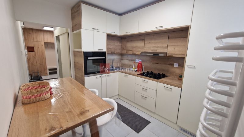 A kitchen in a 3-room apartment with a corner unit and flooring with a wood decor.