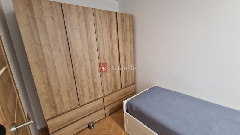 A wardrobe with a wooden decor and a bed in a 3-room apartment.