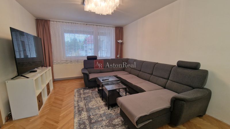 Living room in a 3-room apartment with a dark gray sofa and a television.