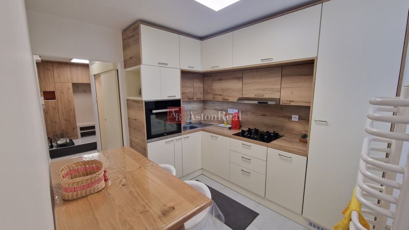 A kitchen in a 3-room apartment with white cabinets and wood decor.