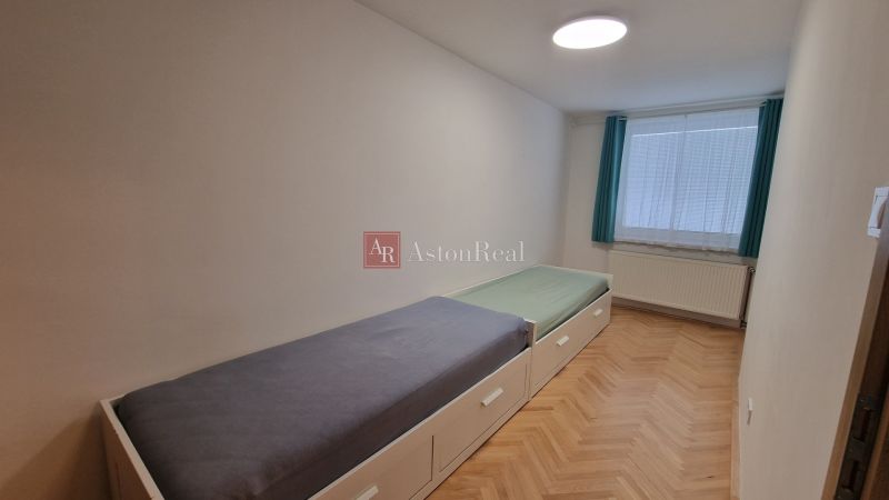 A room in a 3-room apartment with two beds and a floor with a wooden decor.