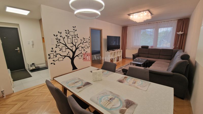 Living room in a three-room apartment with a wooden decor floor and a tree sticker on the wall.
