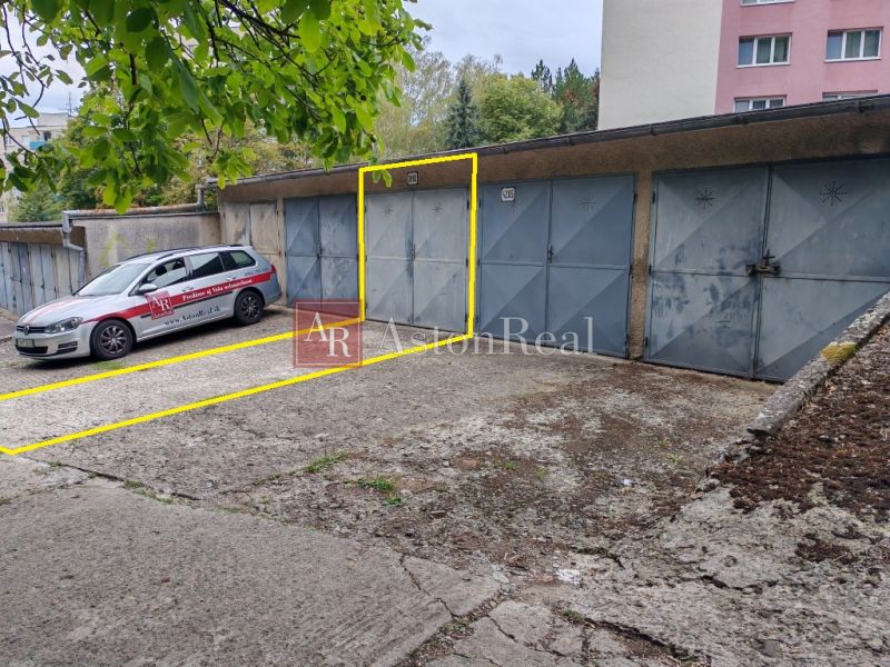 Garages on Partizánska Street in Trenčín, with a car parked under a tree nearby.