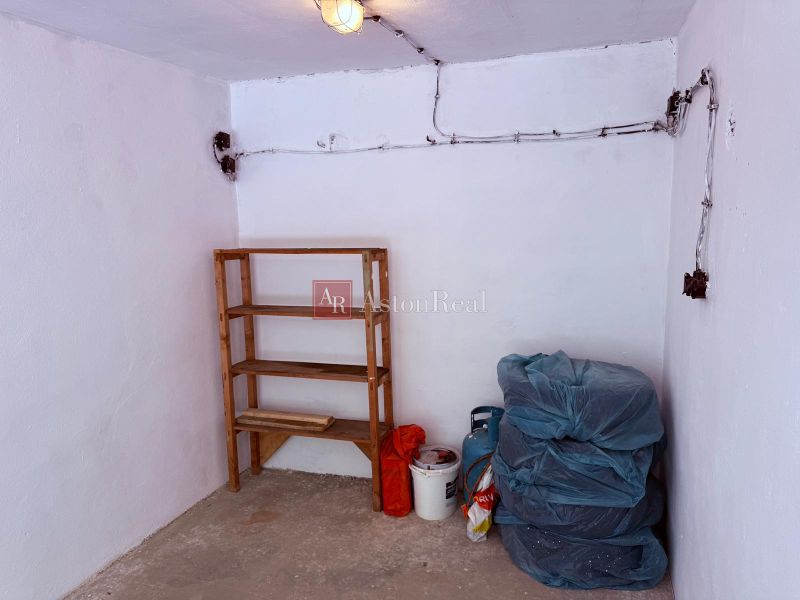 The interior of a garage with a wooden shelf and stored tires.