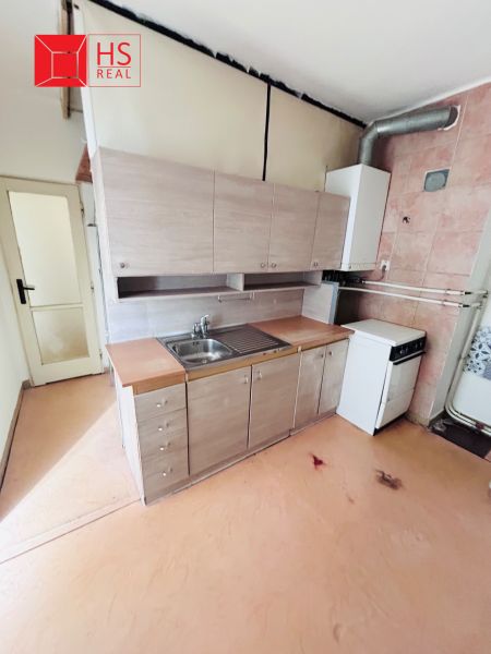 A kitchen in a 2-room apartment with a simple kitchenette and a floor with a wood decor.