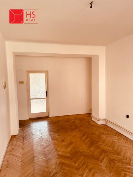 A room in a 2-room apartment with a wooden decor floor and glass doors.