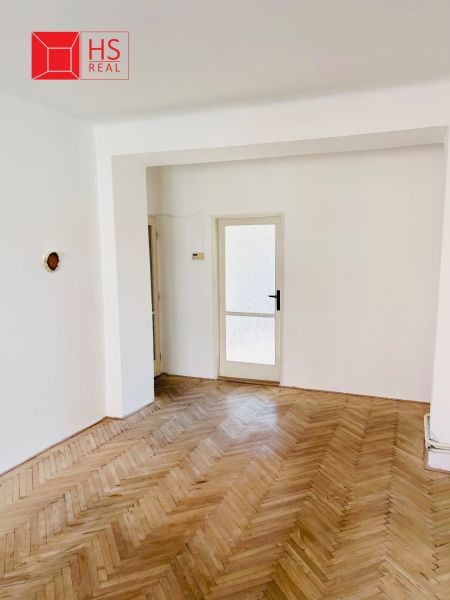 A room with a wooden decor floor and glass doors in a two-room apartment.