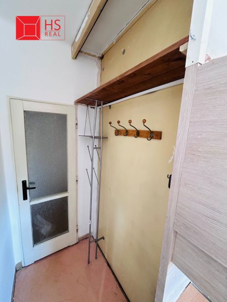 Entrance hallway in a 2-room apartment with a coat rack and a wall shelf.