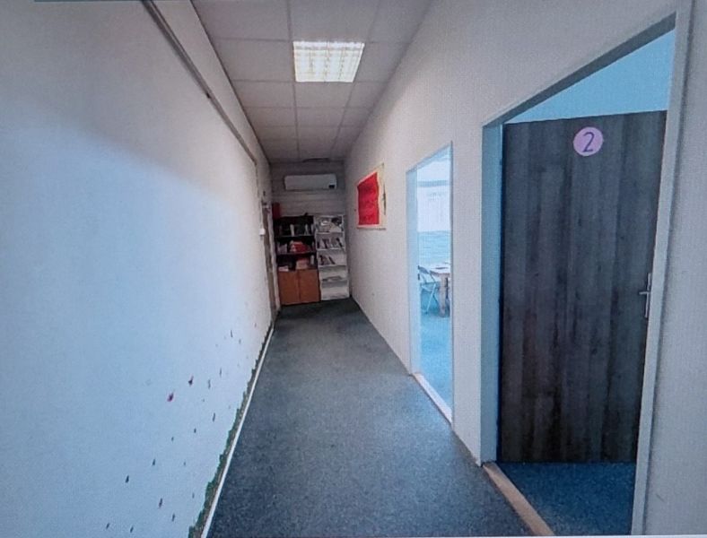 A narrow hallway in an office with doors marked with numbers on the right.