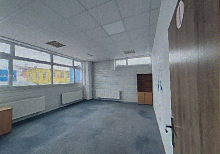 A spacious office with carpeted flooring and large windows.