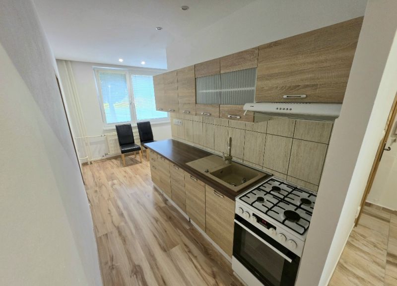 A kitchen with a wood-patterned floor in a 3-room apartment, bright room, appliances.