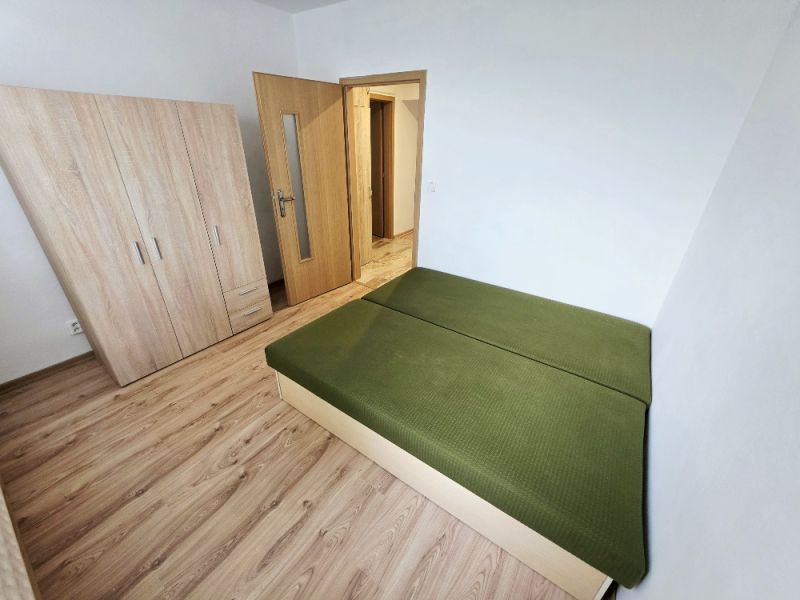 Bedroom in a 3-room apartment with a bed, wardrobe, and wooden decor flooring.