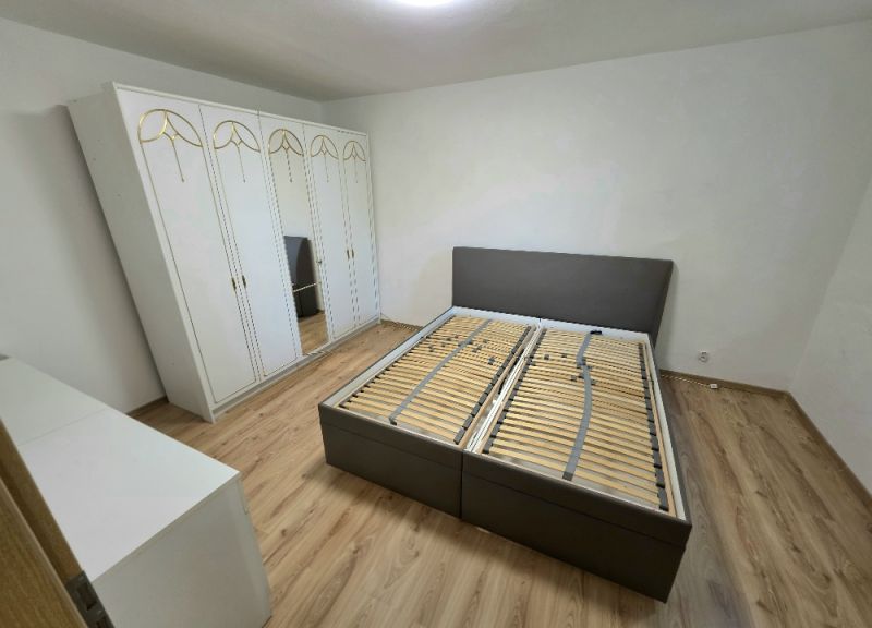 A bedroom in a 3-room apartment with a bed, a wardrobe, and a floor with a wood decor.