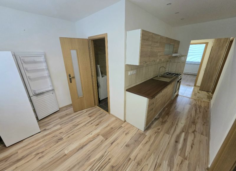 A kitchen in a 3-room apartment with a wood-patterned floor and appliances.
