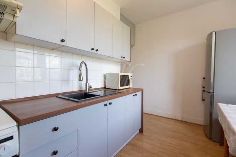 A kitchen with white cabinets, a sink, a microwave, and a wood-patterned floor.