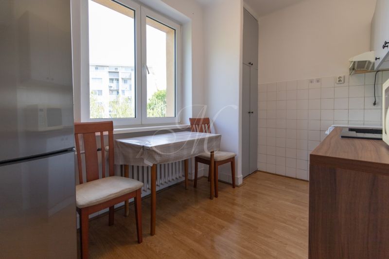 A kitchen in a 3-room apartment with a wooden decor floor, a table, and chairs.