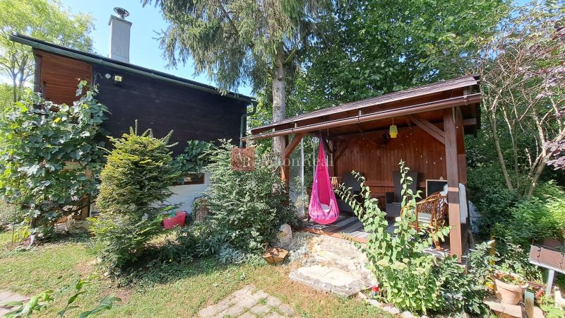 A house on Do Žlebín Street in Ružomberok, surrounded by greenery and a wooden gazebo.