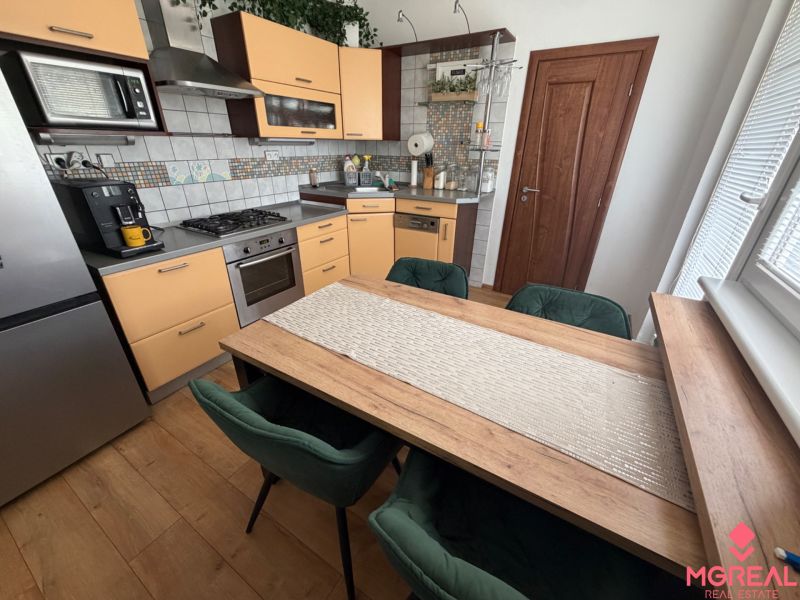 A kitchen with light cabinets and a wood-patterned floor in a three-room apartment.