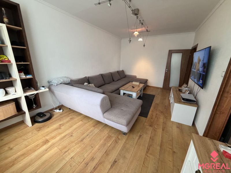 Living room in a 3-room apartment with a sofa and a television, floor with wooden decor.