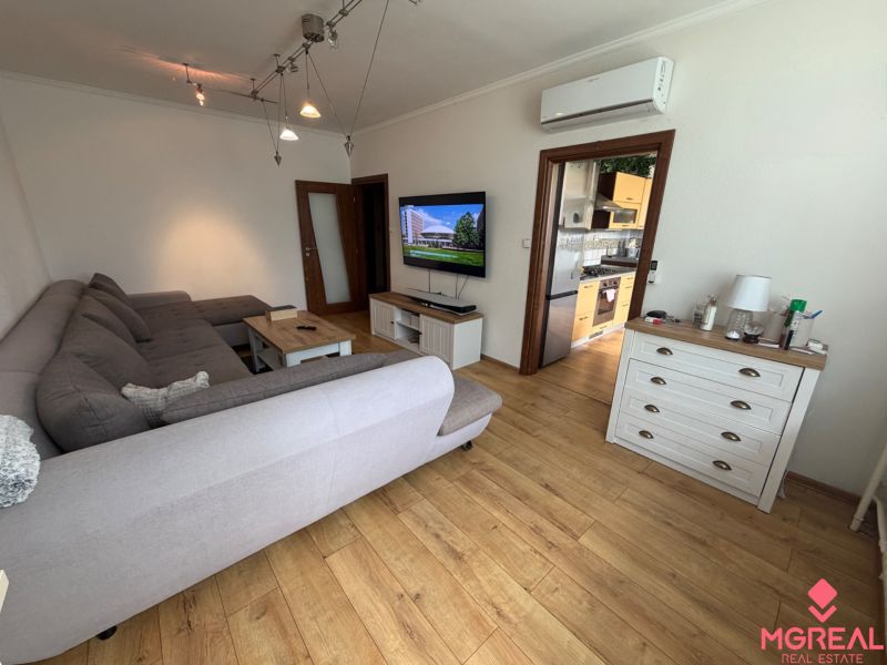 Living room of a 3-room apartment with a spacious sofa and a floor with a wooden decor.