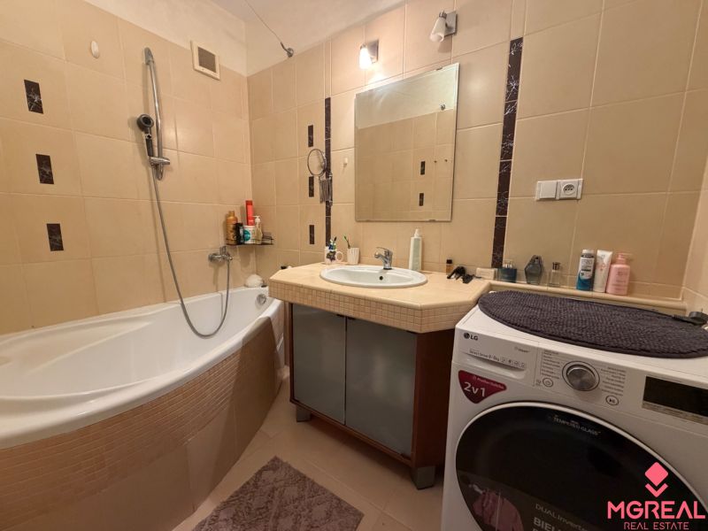 A bathroom in a 3-room apartment with a bathtub, mirror, and washing machine.