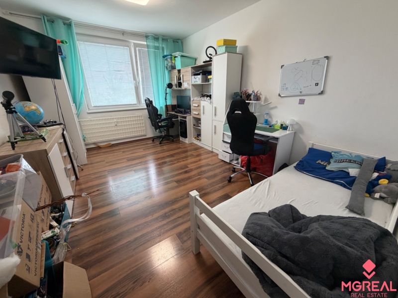 Children's room in a 3-room apartment with a wooden decor floor, a desk, and a bed.