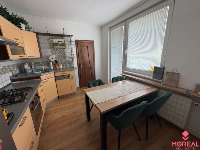 A kitchen in a 3-room apartment with a corner unit and a floor with a wood decor.