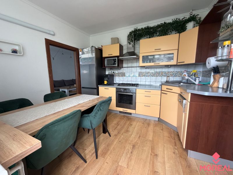 A kitchen in a 3-room apartment with a wooden decor floor and a dining table.